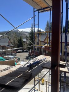 The lower townhomes shown through the scaffolding on the tower building with Baldy peak in the background.