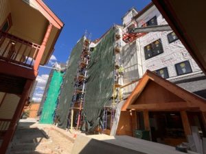 The north side of the tower building is shown behind scaffolding with new siding going in over the front lobby entrance.