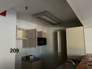 A kitchen shown with drying paint on open cabinet doors and fresh paint on the walls.